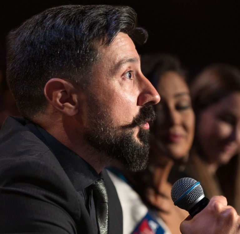 A man talks to the audience with a microphone.